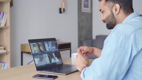 Side View of Indian Man Having Video Call with Diverse People on Pc
