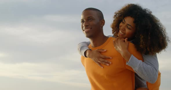 Low angle view of African american man giving piggyback ride to woman on the beach 4k