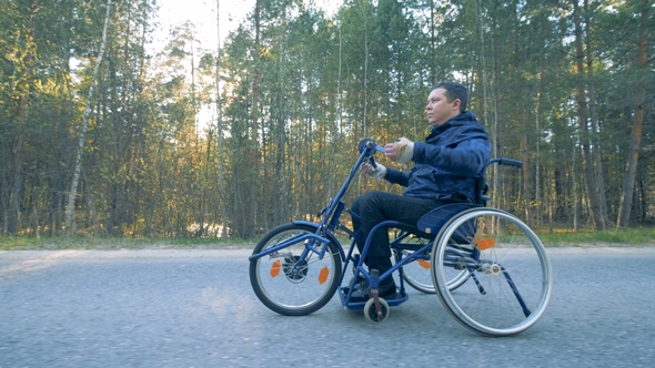 Side View of a Training Wheelchair Getting Moved By a Disabled Person with His Arms