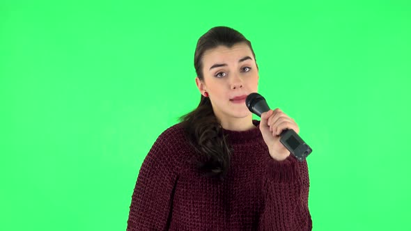 Attractive Girl Sings Into a Microphone and Moves To the Beat of Music. Green Screen