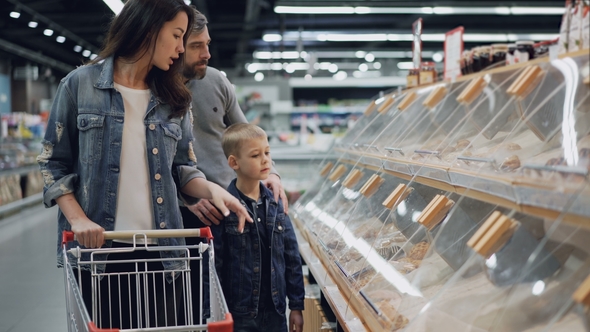 Mother, Father and Their Son Are Shopping for Food in Supermarket Pointing at Plastic Boxes on