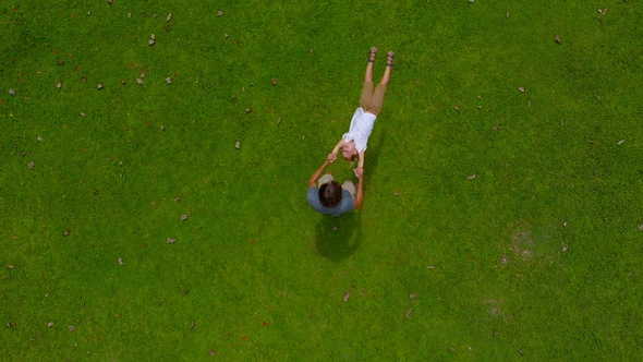 Aerial  Shot of a Father Circling His Son in His Arms on a Green Lawn. Camera Raises Up