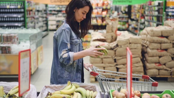 Girl Customer Is Choosing Fruit in Supermarket Buying Bananas Apples and Oranges