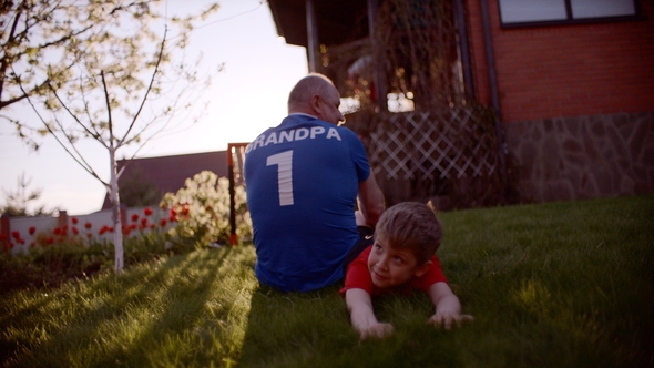 Backshot of Grandfather and Grandson on the Lawn with Soccer Ball on Sunset
