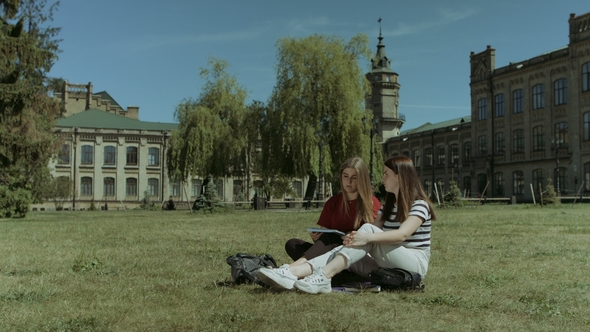 Happy Female Students Relaxing on Campus Lawn