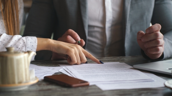 Businessman Signing Contract During Meeting with Business Colleague in Cafe