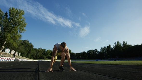 Tattooed Sportsman in Crouch Start on Track