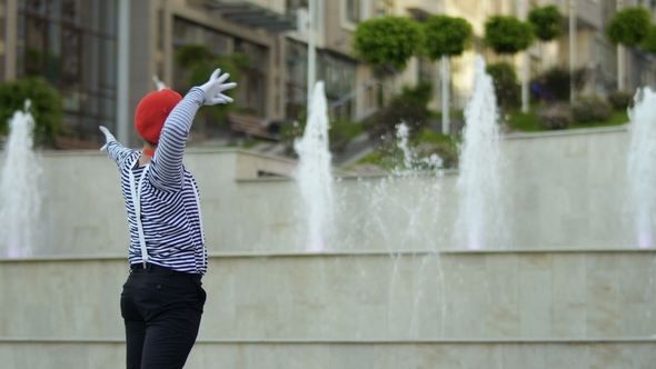 Funny Mime Conductor Gesticulating Hands at Fountain Background