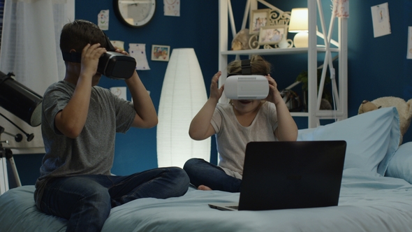 Kids Playing Video Game in VR Goggles on Bed