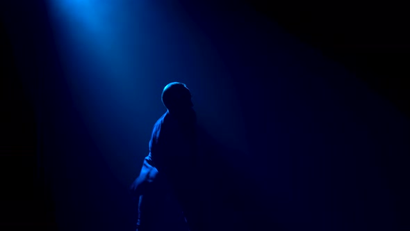 A Middle Aged Man Dances a Latin American Salsa Dance Surrounded By Smoke and Studio Blue Lights