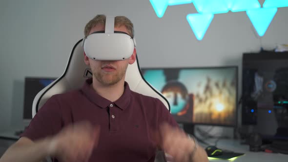 Young attractive male sits in his room, puts on VR goggles