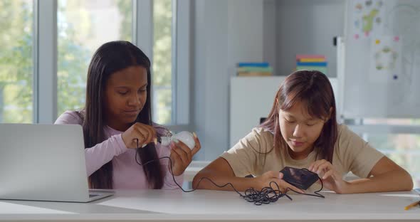 Asian and African Teen Girls with Laptop Computer and Invention Kit at Robotics School Lesson