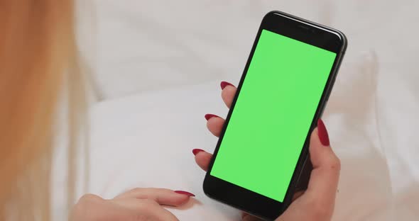 Woman's Holding Mobile Telephone with Green Screen and Looking at the Display