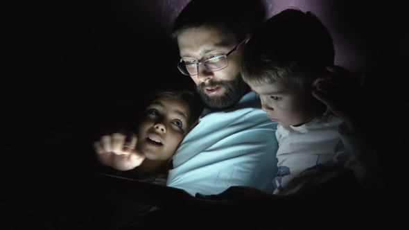 Father with Children Use a Digital Tablet at Night