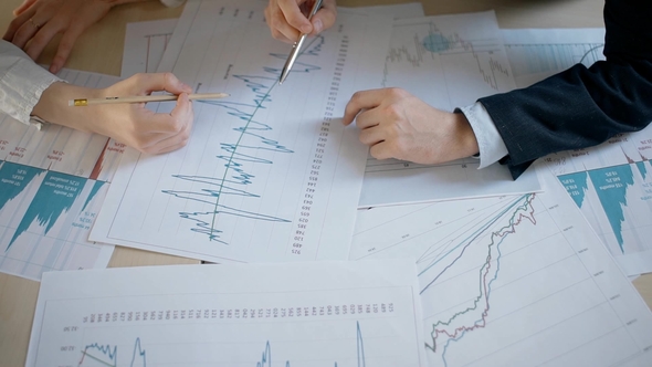 Young Business Couple Are Analyzing New Blueprint Sitting at Table in Workspace.