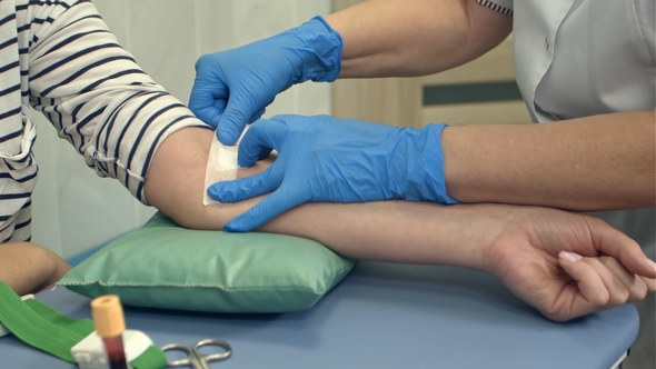 Nurse Putting Plaster on Female Arm After Blood Donation
