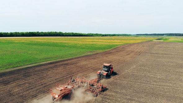Large Scenic Field Is Being Sown By an Agrimotor