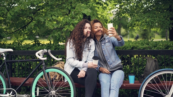 Cheerful Caucasian and African American Girls Friends Are Taking Selfie Making Moustache From Hair