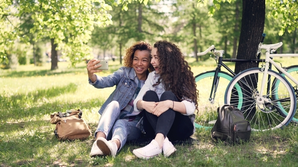 Cheerful Women Are Looking at Smartphone Screen and Laughing Then Taking Selfie Together Posing for