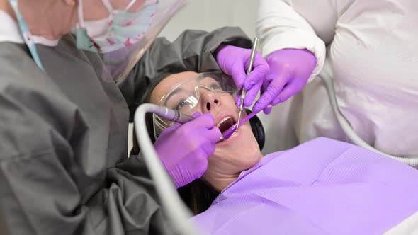 Dentist Hygienist Making Oral Hygienic Cleaning in Dentistry for Young Woman