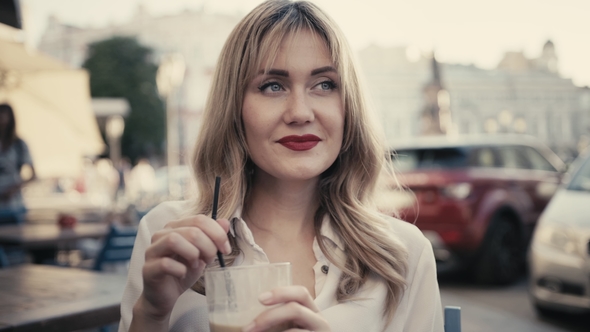 In Paris, a Young Caucasian Blonde Woman, Curly Hair, with Sexy Red Lips, Drinks an Alcoholic