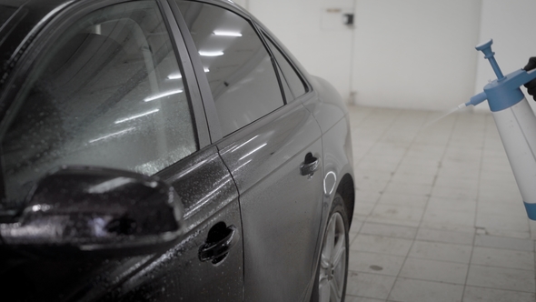 Washerman Is Spraying Water By Nebulizer on a Black Car Body in a Car Wash Box,  of Hands