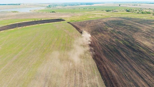 Top View of a Huge Field Getting Sown By a Tractor