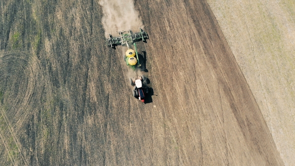 Top View of a Plough Sowing a Massive Field and Raising Dust