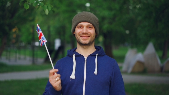 Portrait of Englishman in Sports Clothes Holding Official British Flag Looking at Camera