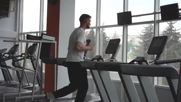 Sport Man Running on Treadmill Machine While Cardio Training in Gym Club.