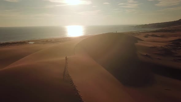 Aerial View of Man Running Along Large Sand Dunes.