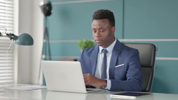 African Businessman Talking on Video Call on Laptop in Office