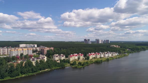 Aerial view of Modern multi-storey houses on the river bank in the city. Around the forest 04