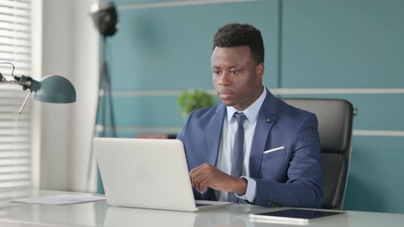 African Businessman Celebrating Success While Using Laptop in Office