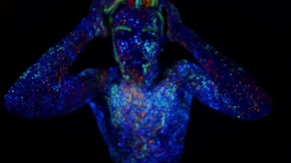 Young Man Painted with Fluorescent Paints Makes Movements with Hands