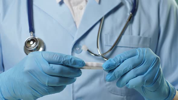 Doctor in Professional Medical Suit and Blue Gloves Checking Temperature By Digital Thermometer