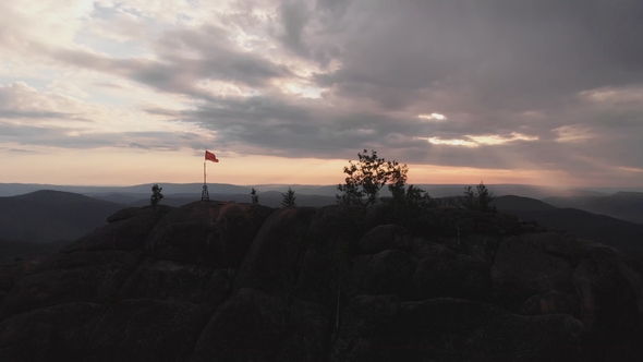 Aerial View of the Red Flag on Top of the Rock in the Siberian Nature Reserve Stolby
