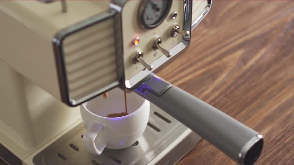 The man turns on the coffee machine in a retro style. Hot fresh coffee flows into a white cup.