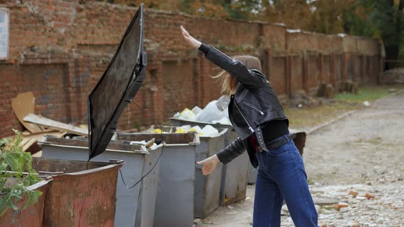 Woman Throws Broken Modern TV Into Trash Cans Concept of Getting Rid of TV Addiction