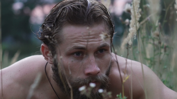 Bearded Man in Fright Looking Around in the Steppe Grass