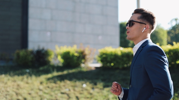 Young Businessman with Sunglasses Listening To the Music on His Smartphone Outdoors and Dancing