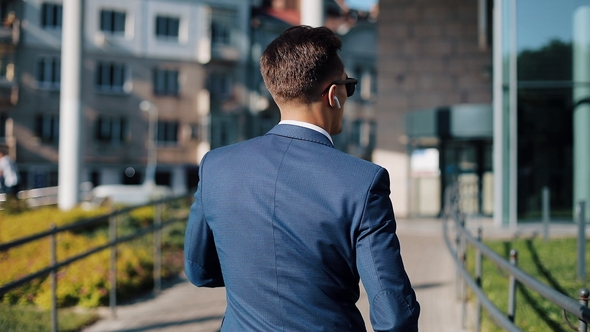 Young Businessman with Sunglasses Listening To the Music on His Smartphone Outdoors and Dancing