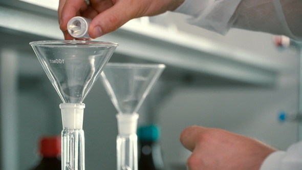 Chemist Pouring Liquids Into a Flask Through Funnel