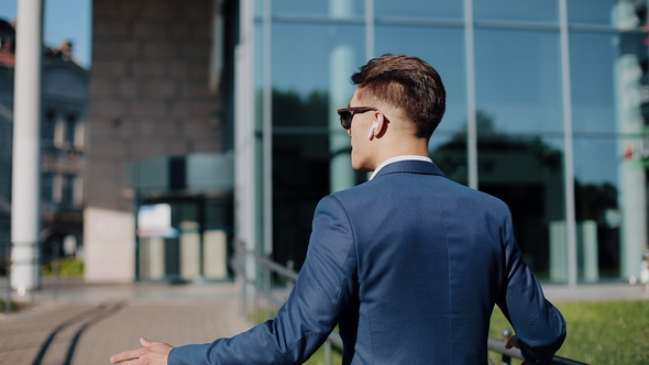 Young Businessman with Sunglasses Listening To the Music on His Smartphone Outdoors and Dancing