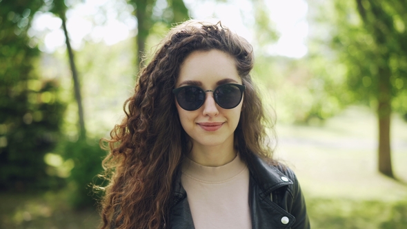 Portrait of Woman in Sunglasses and Trendy Leather Jacket Looking at Camera and Smiling