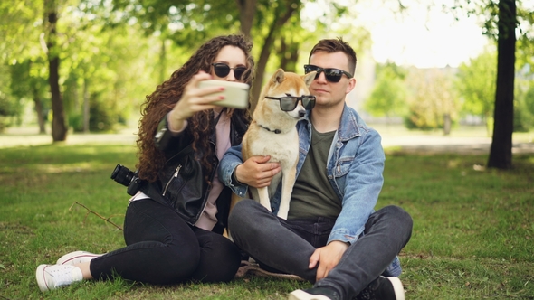 Pretty Woman Is Taking Selfie with Her Boyfriend and Adorable Dog Using Smartphone While Resting in