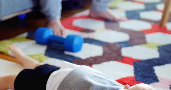 Father exercising while baby boy lying on carpet