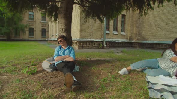 Mixed Race Students Waking Friend Up Throwing Paper Snowballs Outdoors