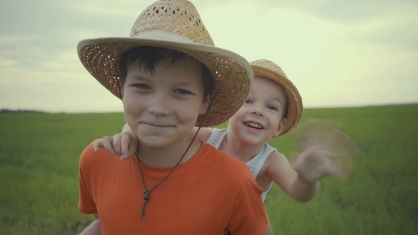 Two Brothers Are Walking in the Field in Straw Hats in the Summer.