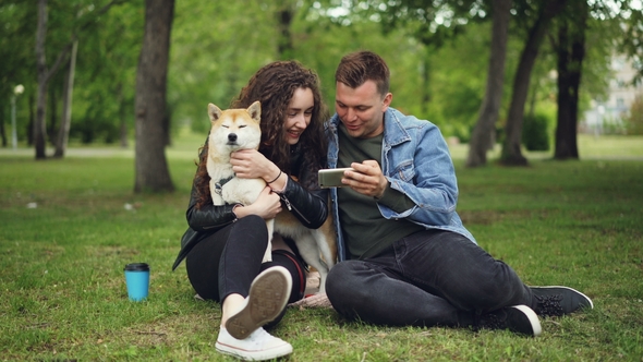 Loving Boyfriend Is Showing Smartphone Screen To Young Lady